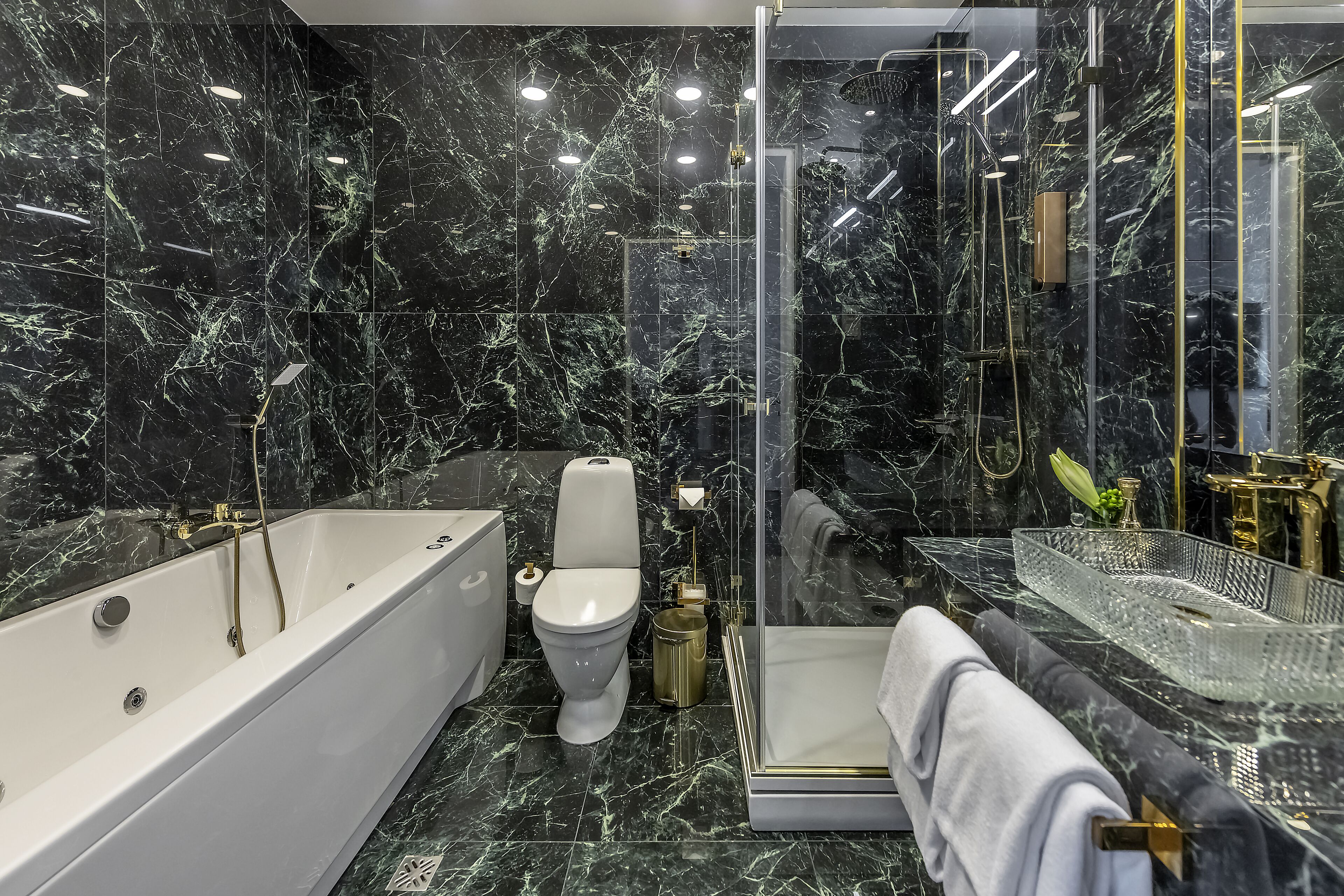 Une salle de bain moderne équipée d’une baignoire, de toilettes et d’une douche séparée par des parois en verre.