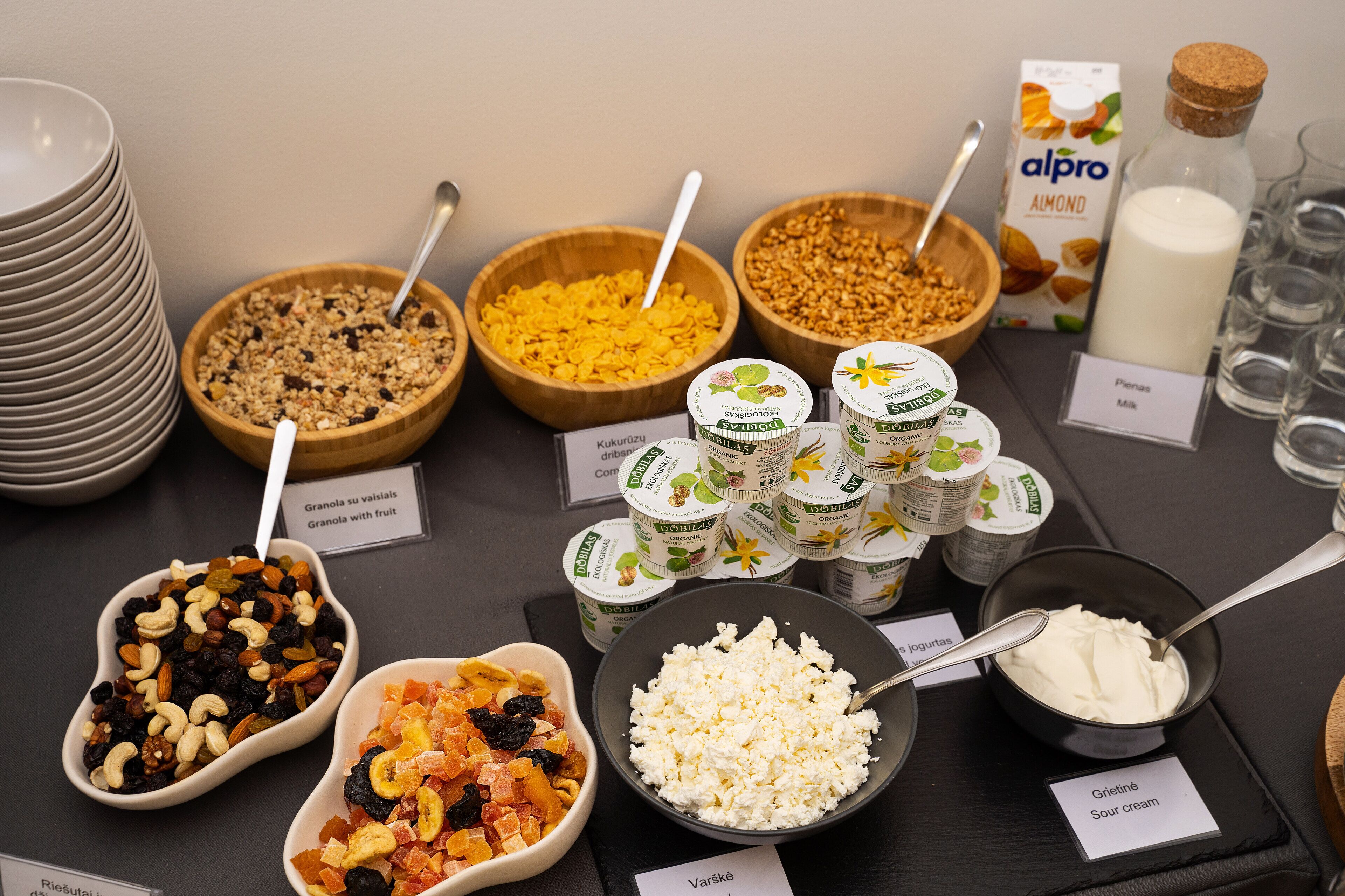 Un bufé con diferentes opciones de comida, entre ellas granola, yogur y queso.