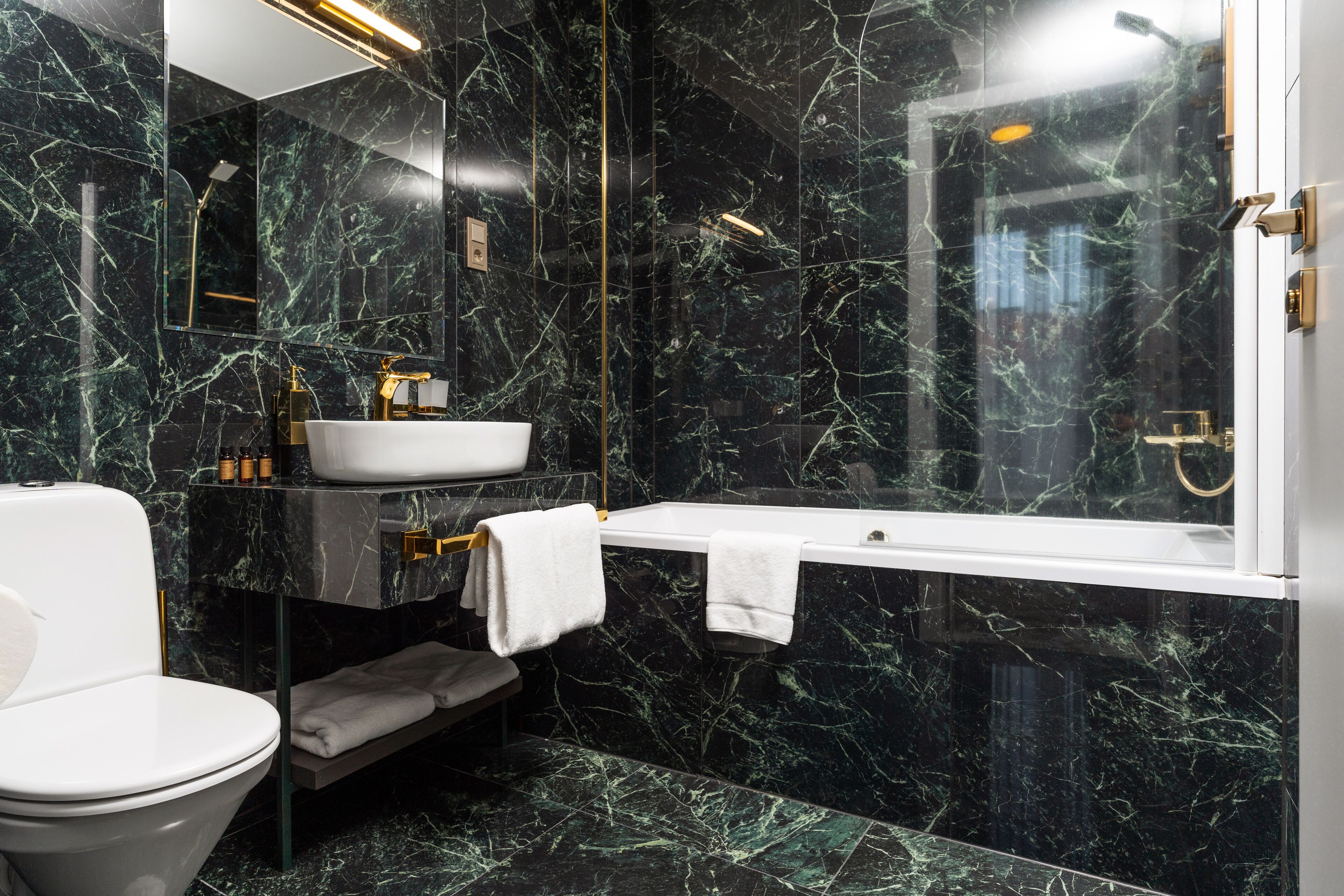 A modern bathroom with a white toilet, a white sink, a bathtub, and a glass-enclosed shower.