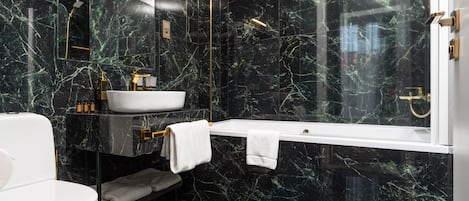 Un bagno moderno con un water bianco, un lavabo bianco, una vasca da bagno e una doccia in vetro.