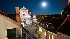 A nighttime view of a church with a bell tower, a staircase, and a street with buildings. - St.Palace hotel (Vilnius)