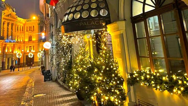 A hotel entrance with a sign reading "PALACE HOTEL," decorated with Christmas lights and garlands. - St.Palace hotel (Vilnius)