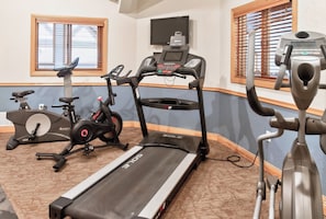 A home gym with a treadmill, stationary bike, elliptical, and a rowing machine.