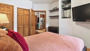 A bedroom with a bed, a desk, a chair, a television, and a wardrobe.