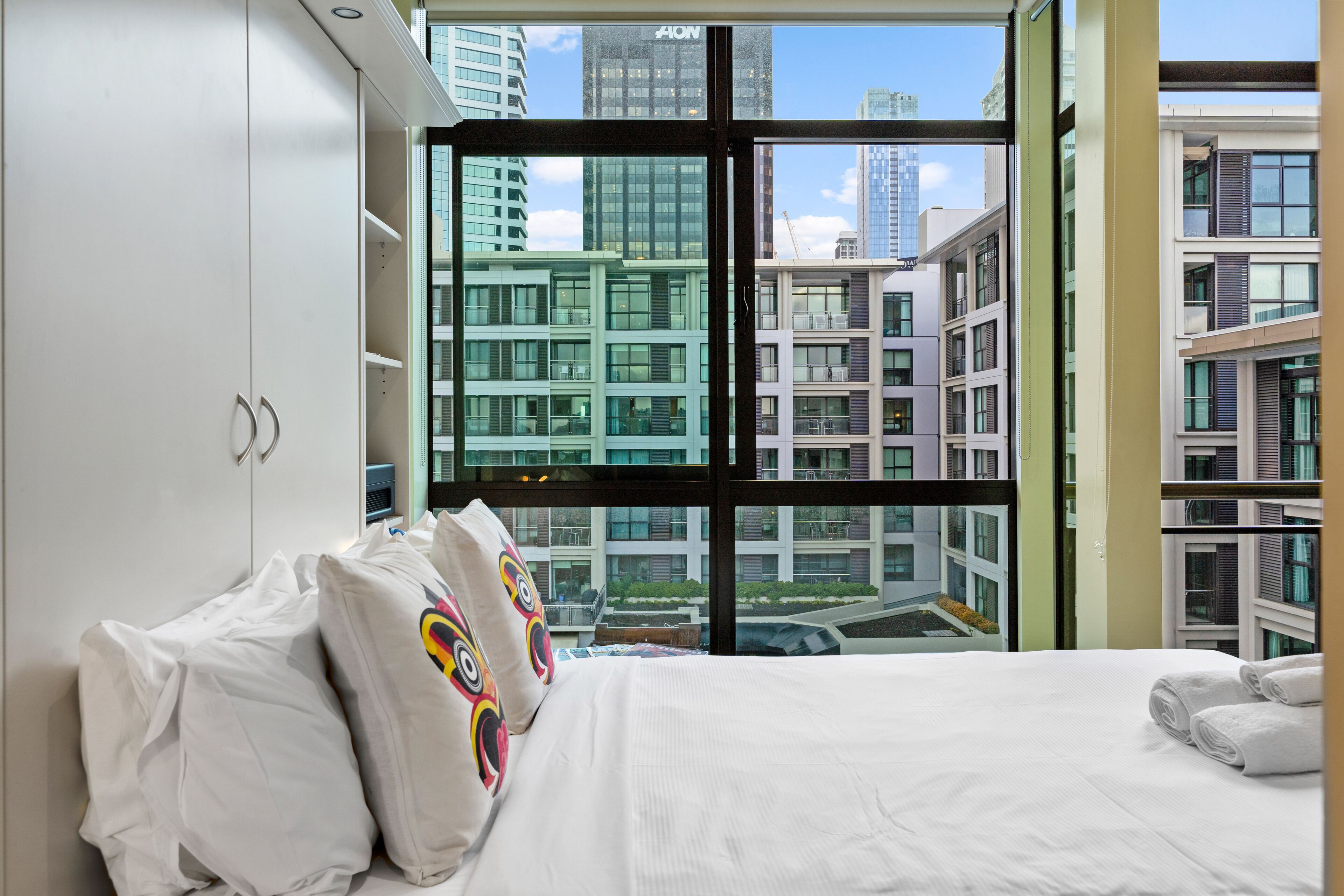 A modern hotel room with a large window offering a view of city buildings.