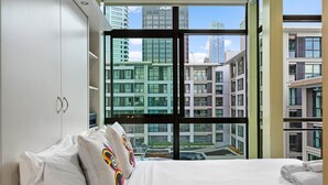Una moderna camera d'albergo con una grande finestra che si affaccia su edifici urbani.