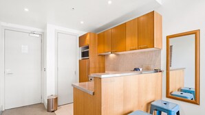 Una cucina compatta con mobili in legno, un piano di lavoro e due sgabelli blu.