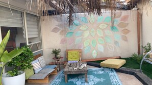 A patio with a wooden bench, a small table, and a colorful wall mural. - Pardes Villa (Pardes Hanna-Karkur)
