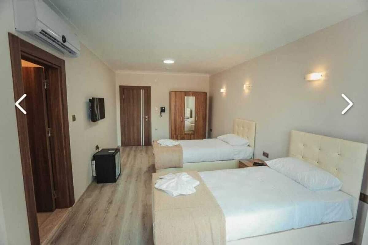 Quarto de hotel com duas camas, televisão, ar condicionado e espelho.