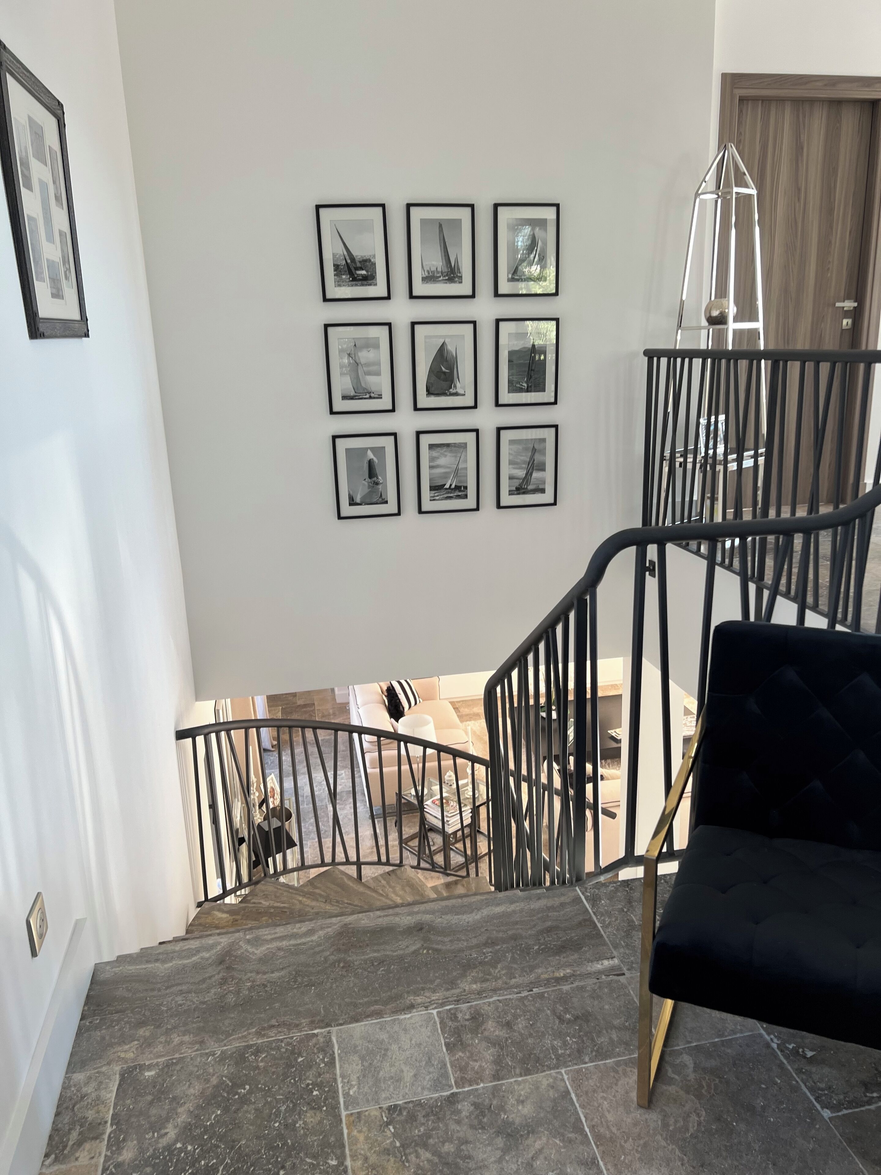 A staircase with a black railing leading to a living area with a black sofa and a coffee table.