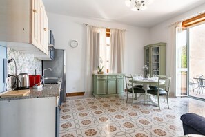 Una cocina con pileta, estufa y placares, un comedor con mesa y sillas, y un piso con diseño.