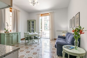 A room with a dining table, chairs, a sofa, a small table with a vase, and a cabinet. - GuestHost - Comfortable 85 sqm apartment that can accommodate up to 4 people, located on the second floor of a renovated building with no lift. The property is located in the center of Palermo, a stone's throw from Villa Giulia, Piazza Magione and the Bo (Palermo)