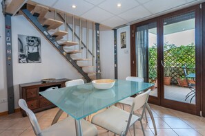 Un espace repas comprenant une table en verre, des chaises, un escalier et une vue sur l’extérieur.