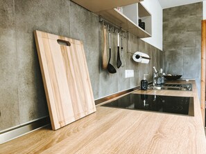 Una cocina moderna con encimera de madera, cocina negra y utensilios colgando.