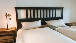 Un lit double avec du linge de lit blanc, une tête de lit en bois et deux oreillers.