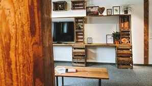 Une pièce comprenant un meuble TV en bois, un téléviseur à écran plat et une table en bois.
