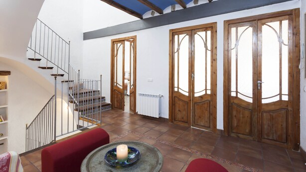 A spacious living area with a staircase, wooden doors, and a tiled floor. - Ca la Partida (San Rafael del Río)
