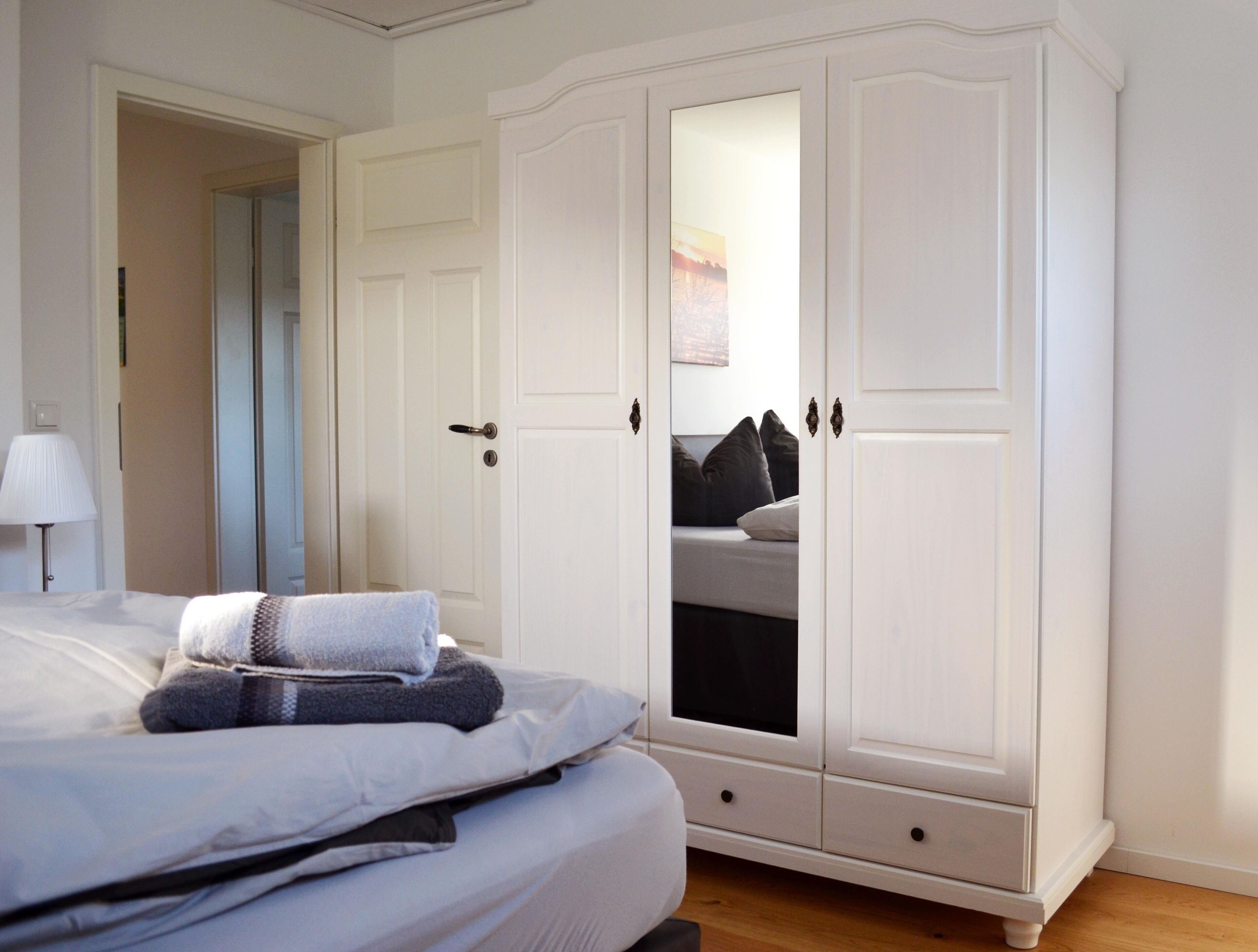 A bedroom with a bed, a wardrobe, and a nightstand.