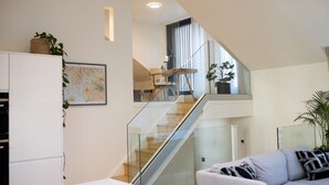 Una sala de estar moderna con una escalera, un sofá y un comedor.