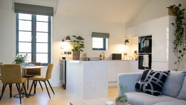 Una cocina moderna con una isla central, comedor con sillas y un sofá.