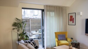 Una sala de estar moderna con un sofá, un sillón amarillo, una mesita de centro y una planta en maceta.