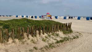 A sandy beach with a playground and portable toilets.
