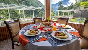 A dining table set with breakfast plates, including eggs and bacon, and a variety of beverages. - Bhotekoshi Heli Resort and Spa (Marming)