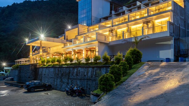 A modern hotel with multiple floors, large windows, and a stone retaining wall. - Bhotekoshi Heli Resort and Spa (Marming)