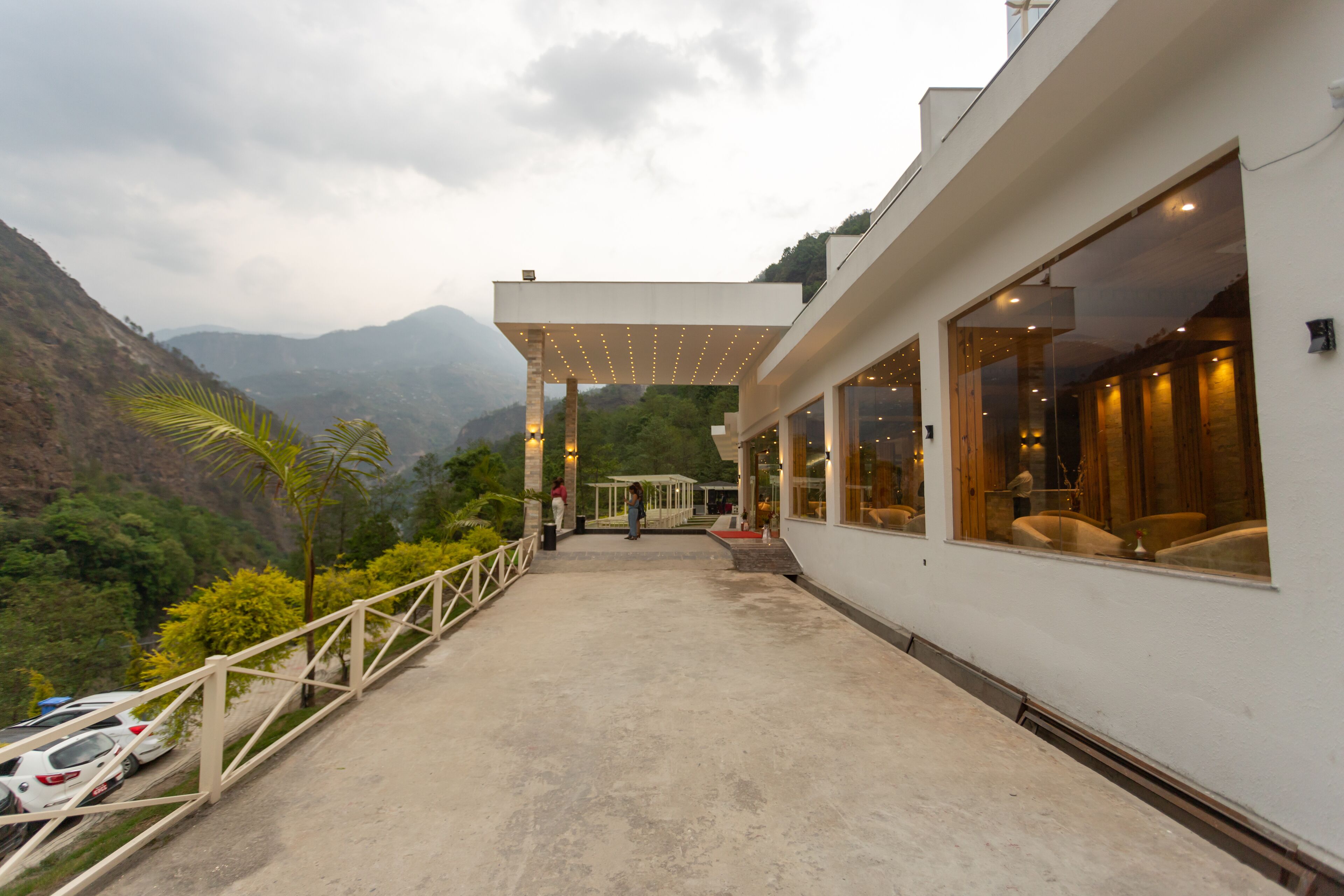 Un hotel con un espacio exterior cubierto, vistas de las montañas circundantes y un camino pavimentado.