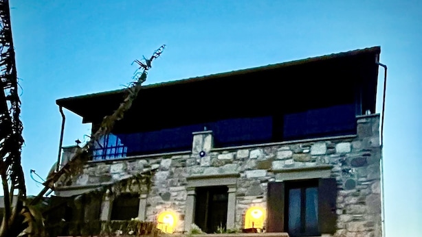 A stone building with an archway entrance, outdoor lighting, and a flower bed. - Ionia Liberty Stone Hotel (Foça)