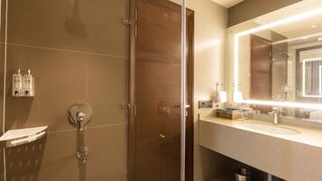 A modern bathroom with a glass shower enclosure, a vanity with a large mirror, and a sink.