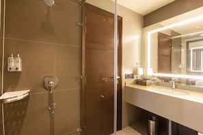 A modern bathroom with a glass shower enclosure, a vanity with a large mirror, and a sink.