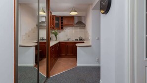 Eine kompakte Küche mit Holzausstattung, einer weißen Arbeitsplatte und einer Uhr an der Wand.