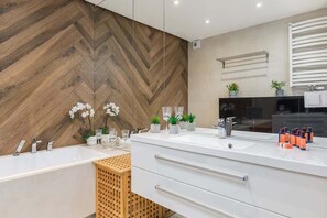 Un baño moderno con un espejo grande, tocador blanco y pared de madera con diseño de espiga.