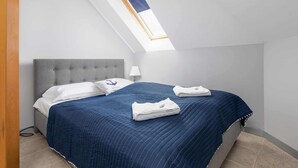 A bedroom with a bed, a nightstand, a lamp, a window with a view, and a ceiling with a skylight. - Family Apartment for 6 Persons | Close to the Beach and Parking (Pobierowo)