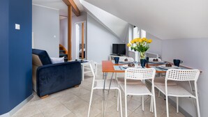 A modern loft-style room with a dining area, a sofa, and a TV. - Family Apartment for 6 Persons | Close to the Beach and Parking (Pobierowo)