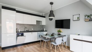 Una cocina moderna con armarios blancos, encimera negra y una zona de comedor con mesa y sillas.