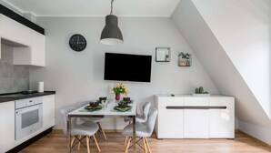 Una cocina moderna con comedor, un televisor de pantalla plana en la pared y una planta pequeña en el aparador.