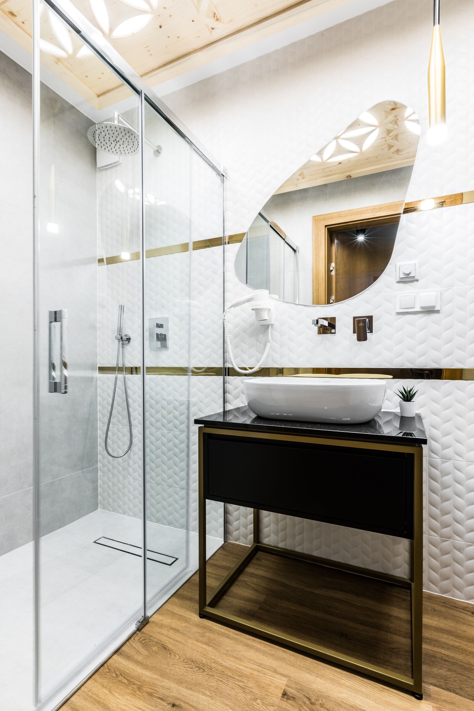 A modern bathroom with a glass-enclosed shower, a white sink, and a wooden vanity.