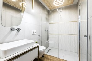 A modern bathroom with a white sink, toilet, and glass shower enclosure. - Aparthotel Prestige  (Zakopane)