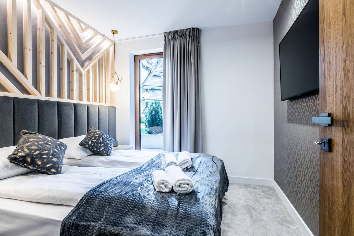 Habitación de hotel moderna con cama, televisión y vistas al exterior.