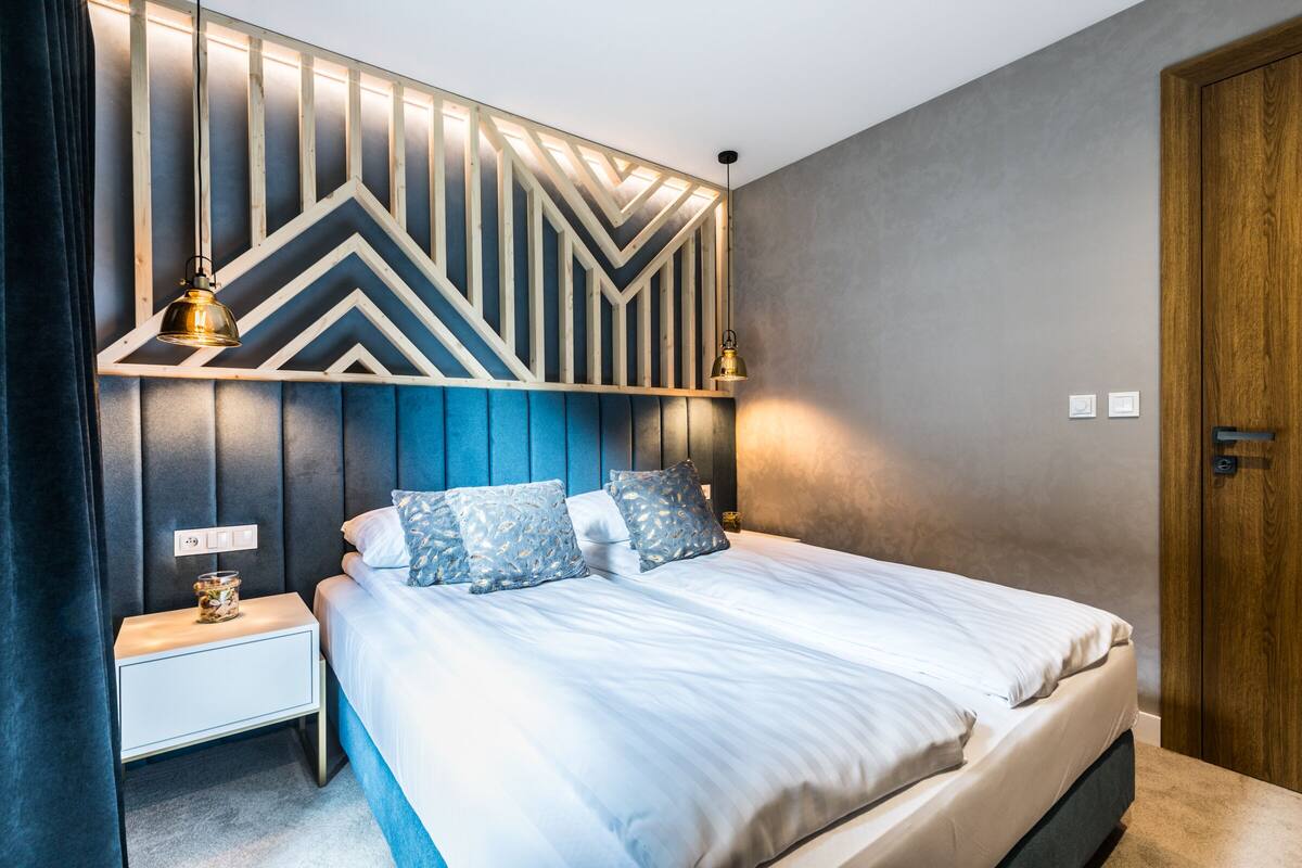 Un dormitorio moderno con una cama, mesitas de noche y un llamativo cabecero geométrico.