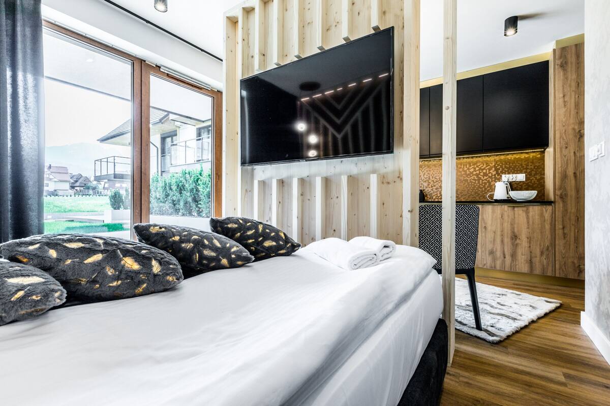 Una habitación de hotel moderna con una cama grande, un televisor de pantalla plana montado en la pared y vistas al exterior.