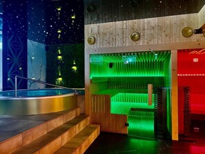 A modern indoor pool area with a wooden deck and a green-lit relaxation zone. - Aparthotel Prestige  (Zakopane)