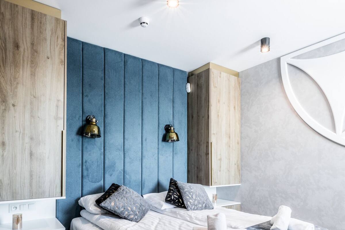 Un dormitorio moderno con una cama grande, un armario de madera y dos lámparas de pared.