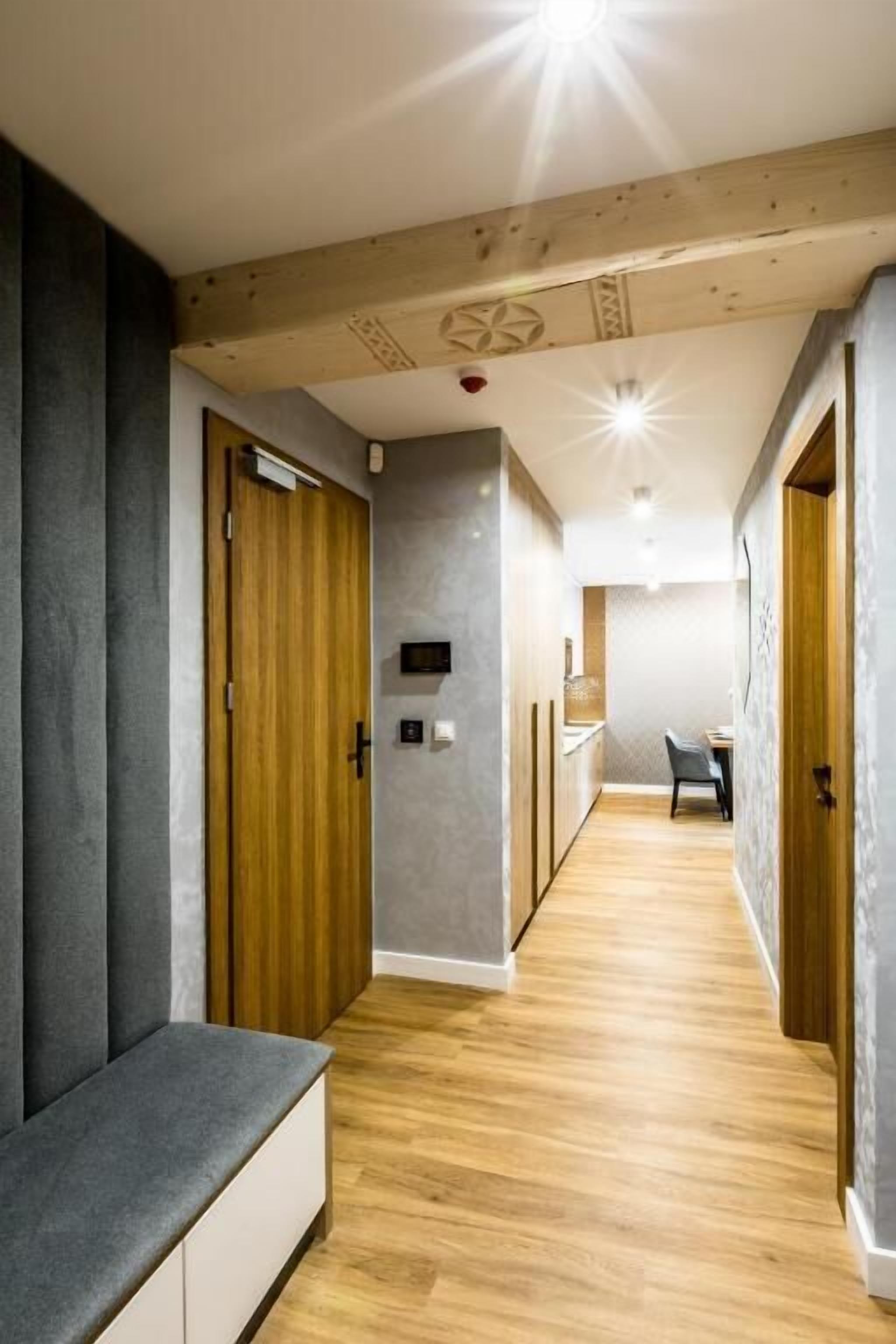 Un couloir avec des portes en bois, un banc et un coin repas comprenant une table et des chaises.