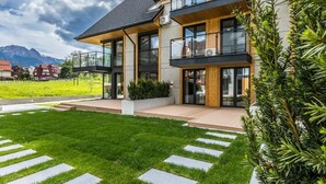 Una casa moderna de dos pisos con un césped cuidado y piedras que guían al acceso.