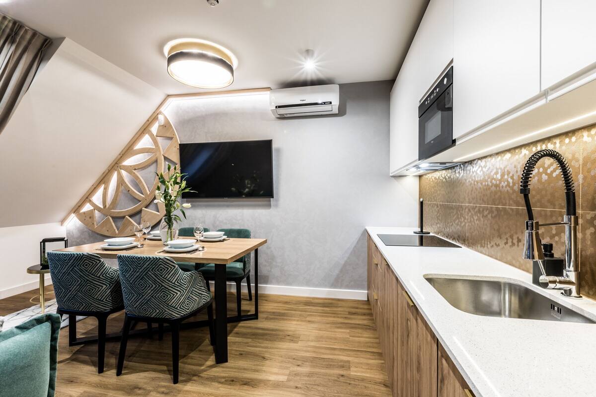 Una cocina moderna con horno empotrado, un lavamanos y un comedor con mesa y sillas.