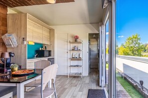 Una cocina moderna con armarios de madera, una mesa de comedor con sillas y vistas al exterior a través de amplios ventanales correderas.