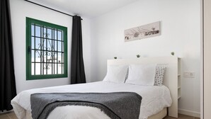 Una camera da letto con un letto, una finestra con inferriate, una testiera e un'opera d'arte appesa al muro.